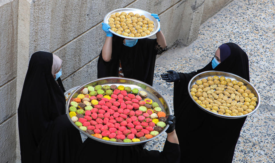 Iraqi women carry cookies for the upcoming Muslim Eid al- Fitr celebrations, that marks the end of the Muslim holy fasting month of Ramadan, in Basra, Iraq, Friday, May 22, 2020. (AP Photo/Nabil al-Jurani)