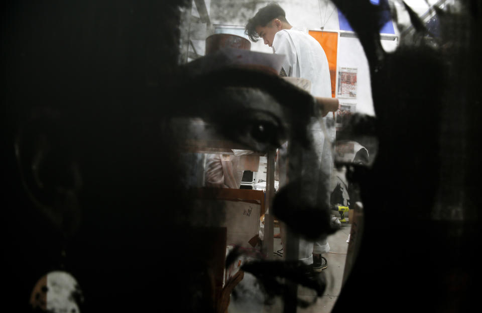 ARCHIVO - Un artista hace serigrafías en el fondo del rostro de Frida Kahlo impreso en la instalación de arte de los artistas Rirkrit Tiravanija y Tomas Vu, en la galería Untitled Art durante Art Basel, el 6 de diciembre de 2018, en Miami Beach, Florida. El 70 aniversario de la muerte de Kahlo es el 13 de julio de 2024. (AP Foto/Brynn Anderson, Archivo)