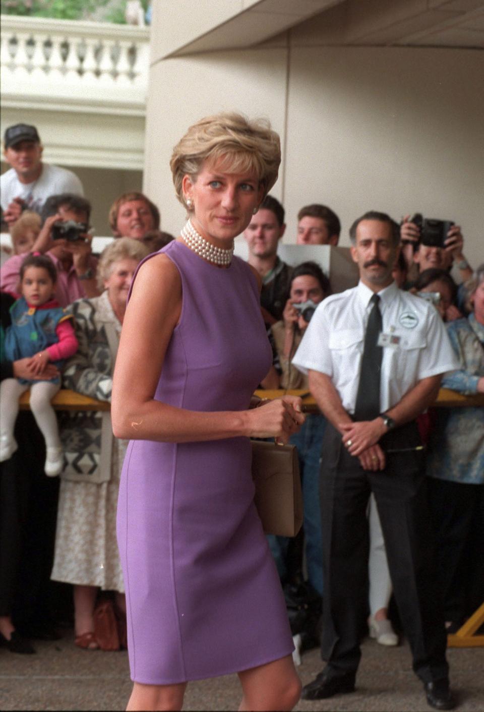 In one of her more reserved looks in 1996, Diana chose a lilac shift dress with a pearl choker, neither of which would look out of place today, either in the workplace or during an evening dinner out. (Getty Images)