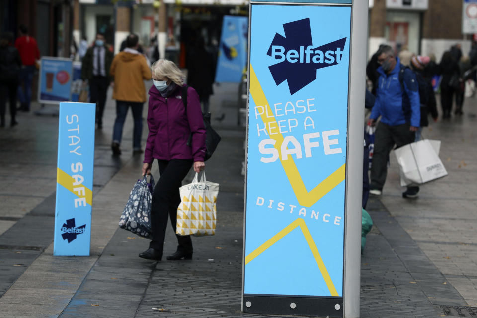 A woman wears a face mask in Belfast city centre, Northern Ireland, Wednesday, Oct. 14, 2020. Northern Ireland introducing the tightest COVID-19 restrictions in the United Kingdom on Wednesday, closing schools for two weeks and pubs and restaurants for a month. “This is not the time for trite political points," First Minister Arlene Foster told lawmakers at the regional assembly in Belfast. “This is the time for solutions." (Brian Lawless/PA via AP)