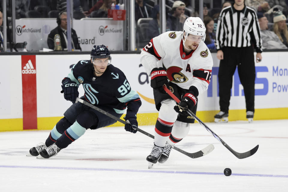 Ottawa Senators defenseman Thomas Chabot (72) works to control the puck with Seattle Kraken left wing Andre Burakovsky (95) trailing during the third period of an NHL hockey game Thursday, Jan. 4, 2024, in Seattle. The Kraken won 4-1. (AP Photo/John Froschauer)