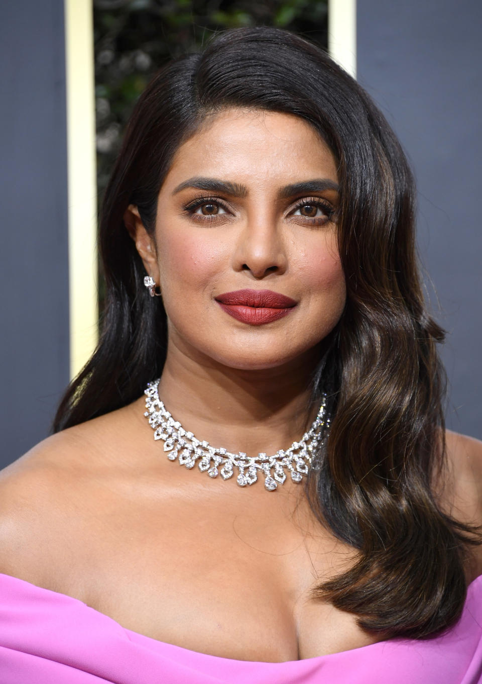 A closeup of Priyanka at a red carpet event where she's wearing a diamond necklace and an off-the-shoulder dress