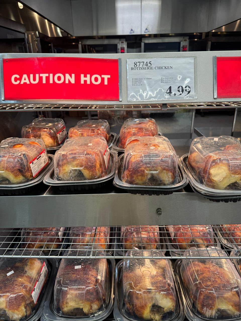 Costco rotisserie chicken display in store with $4.99 price tag above it