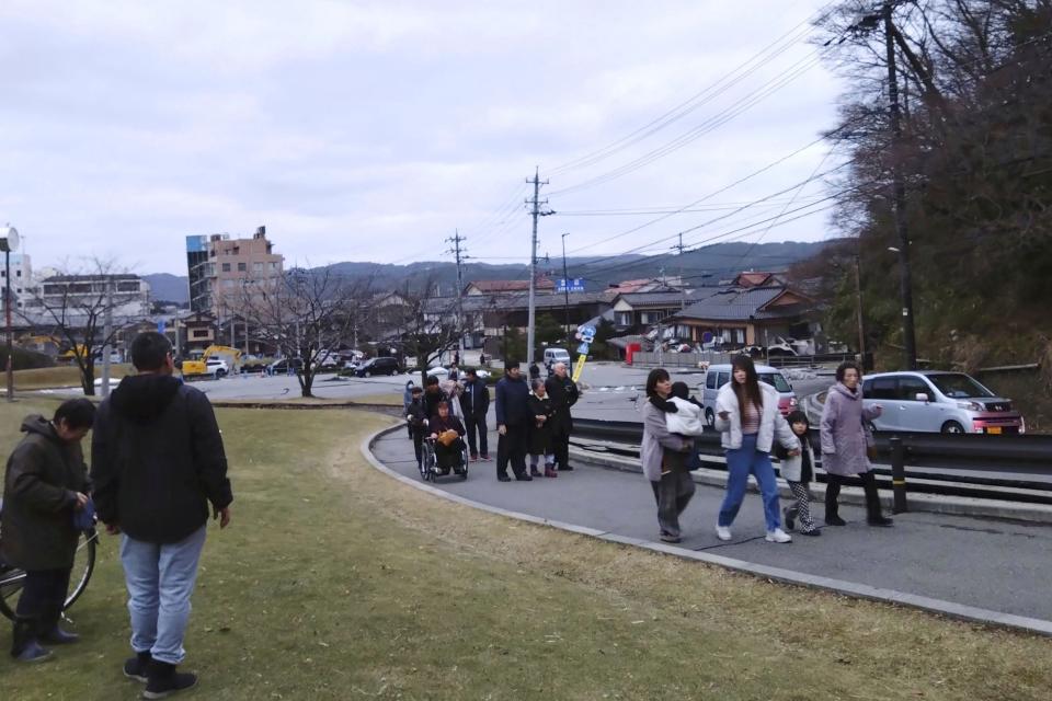 People walk to a higher place to take shelter after an earthquake in Wajima, Ishikawa prefecture, Japan Monday, Jan. 1, 2024. Japan issued tsunami alerts Monday after a series of strong quakes in the Sea of Japan.(Kyodo News via AP)