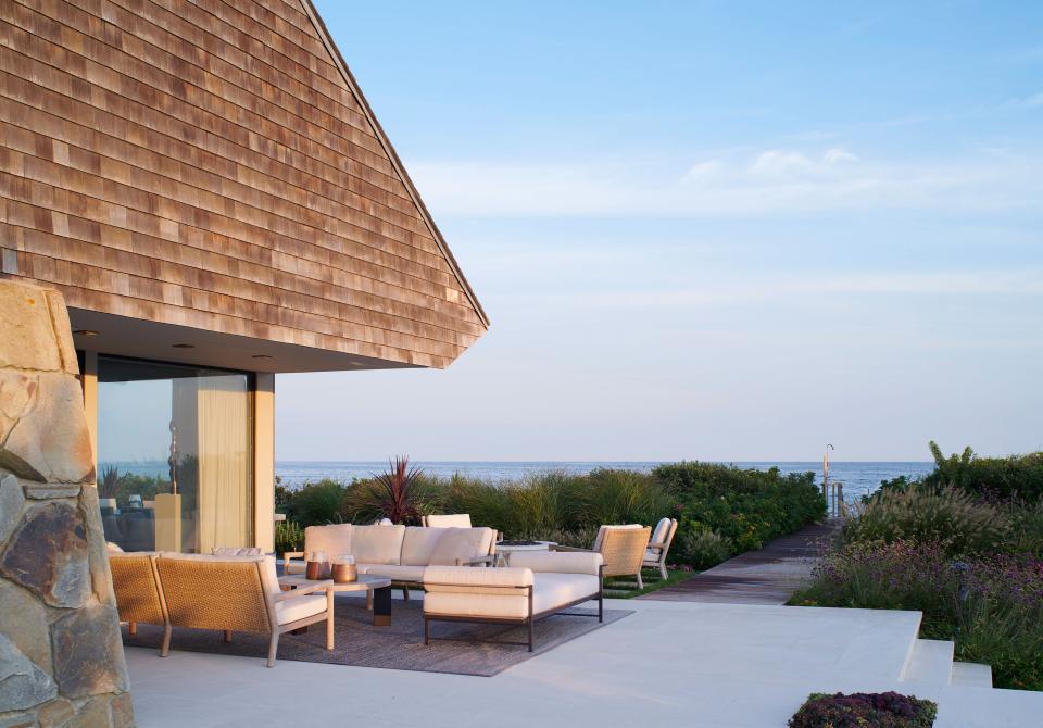 “We usually have a full house of family and friends during the summer and wanted to create a welcoming, relaxing atmosphere,” says the wife, adding that it was important for guests to feel they could “flow” through the common areas of the house. This outdoor deck just outside the dining room is furnished with a pair of Franck sofas by Sutherland Furniture in weathered teak.