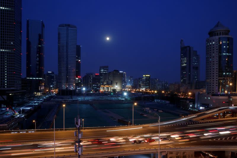 The supermoon shines over the Central Business District as cars move along a thoroughfare during evening rush hour in Beijing