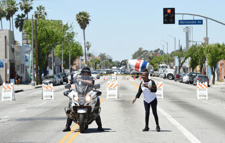 A protester takes direction from an Los Angeles Police Department officer at the intersection of Florence and Normandie Avenue, the flashpoint where the riots started 25 years ago, during a march and rally to remember and honor the victims of the 1992 Los Angeles riots in Los Angeles, California, U.S., April 29, 2017. REUTERS/Kevork Djansezian