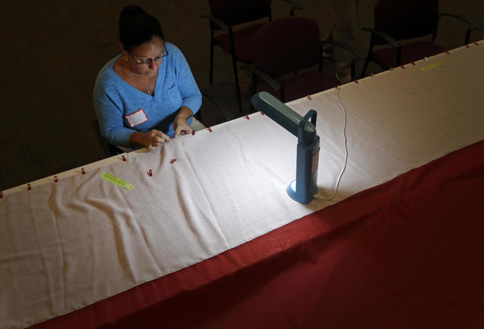 In this July 22, 2013 picture, volunteer Jan Lucas sews along the edge of a replica of the star-spangled banner in Baltimore as part of a project to commemorate the creation of the flag that inspired America’s national anthem. The project began July 4 in Baltimore, and it is expected to take volunteers six weeks to hand sew the estimated 150,000 stitches in the famous flag. When finished, it will be about a quarter of the size of a basketball court. (AP Photo/Patrick Semansky)