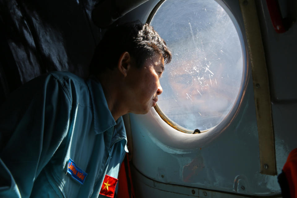 Officer Lang Van Ngan of the Vietnam Air Force looks out the window onboard a flying AN-26 Soviet made aircraft during a search operation for the missing Malaysia Airlines flight MH370 plane over the southern sea between Vietnam and Malaysia Friday, March 14, 2014. Vietnam says it has downgraded but not stopped its search for the missing jetliner in the South China Sea and has been asked by Malaysian authorities to consider sending planes and ships to the Strait of Malacca. (AP Photo/Na Son Nguyen)