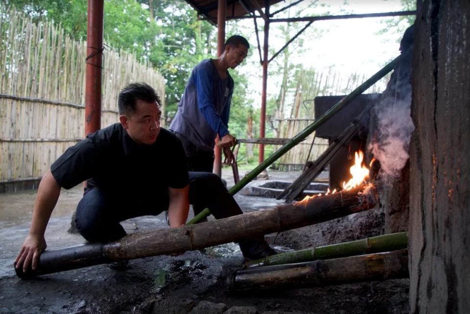 Concordia moving a burning bamboo stick into place, so that they can begin cooking.