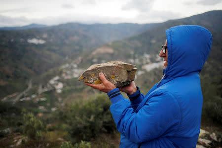 Carlos Sanz, 74, shows a "Pizarra" (slate) stone, which is the same rocky material of the area (rear) where Julen, a Spanish two-year-old boy fell into a deep well six days ago when the family was taking a stroll through a private estate, in Totalan, southern Spain, January 19, 2019. REUTERS/Jon Nazca