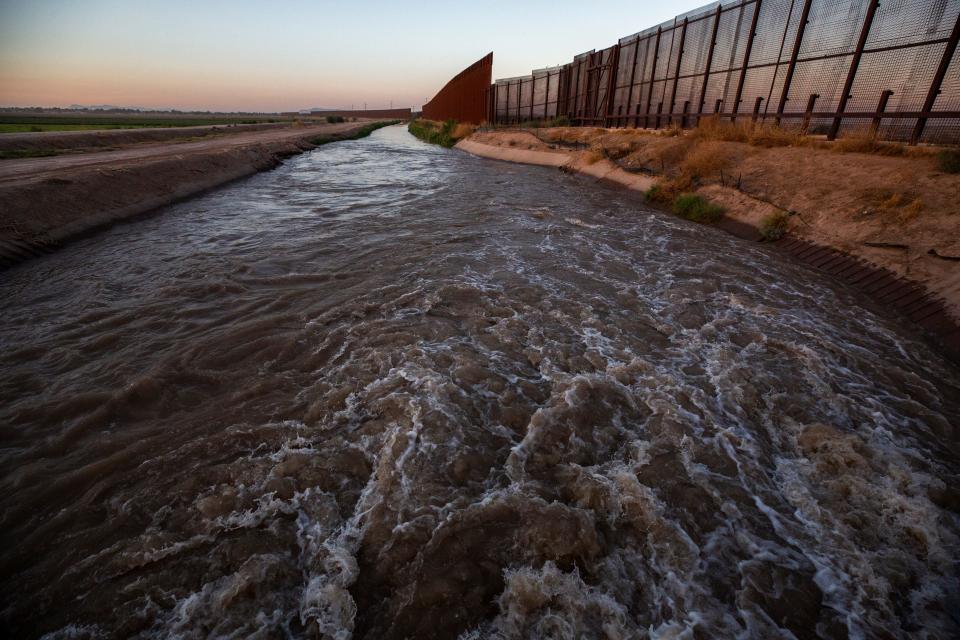 A strong current flows in the main canal next to the border wall in the lower valley of El Paso, Texas during irrigation season in June 2023.