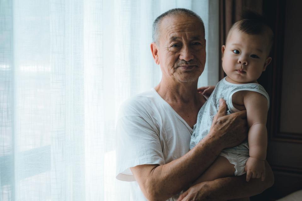 Old man carrying infant or grandparent holding their grandchild