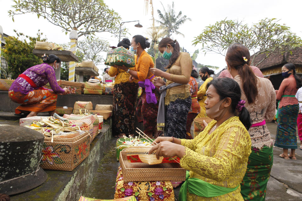 Women wearing face masks as a precaution against the new coronavirus outbreak participate in a Hindu ritual at a temple in Bali, Indonesia, Wednesday, Sept. 16, 2020. (AP Photo/Firdia Lisnawati)