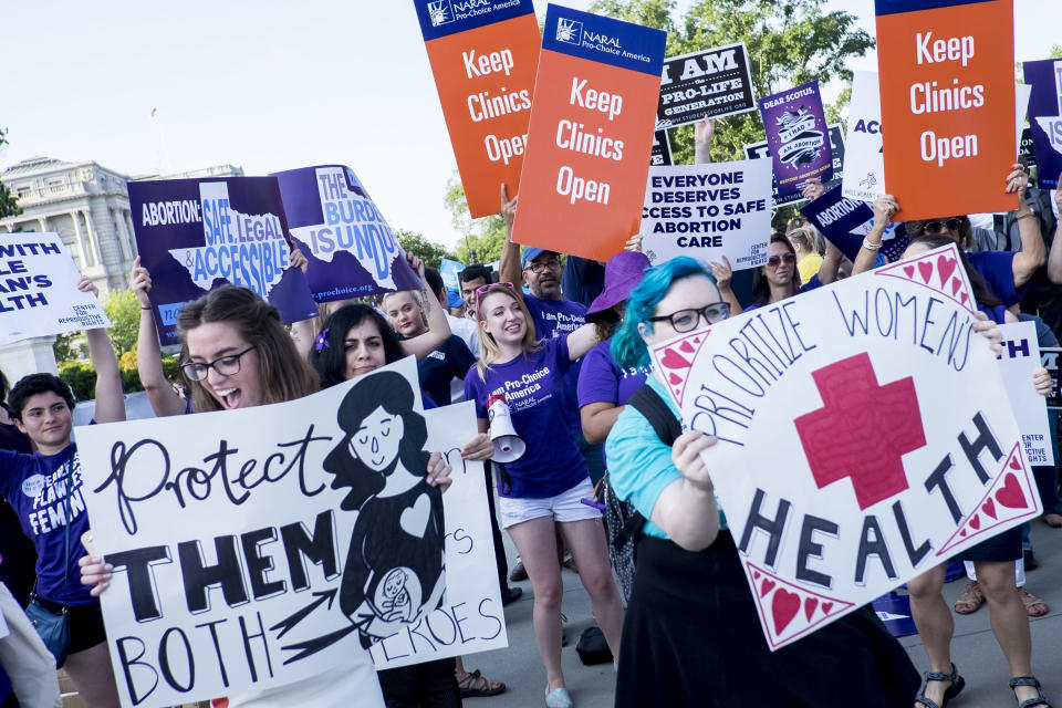 Demostrators hold signs reading "keep clinics open" and "prioritize women's health"