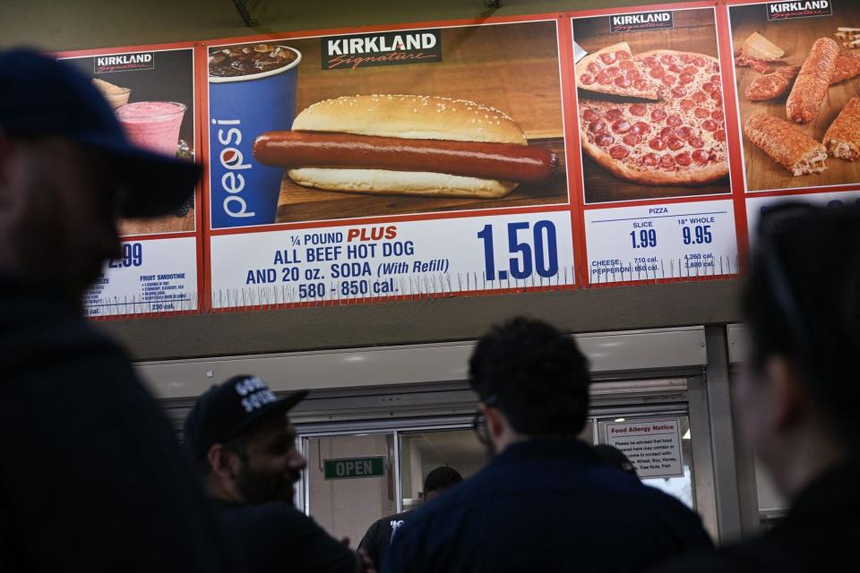 Customers wait in line to order below signage for the Costco Kirkland Signature $1.50 hot dog and soda combo, which has maintained the same price since 1985 despite consumer price increases and inflation, at the food court outside a Costco Wholesale Corp. store on June 14, 2022 in Hawthorne, California. (Photo by Patrick T. FALLON / AFP) (Photo by PATRICK T. FALLON/AFP via Getty Images)