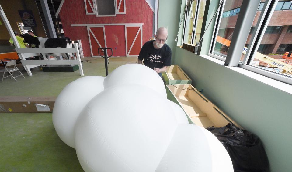 Steve Soucie inflates a cloud to be used in the farm area inside the Experience Children's Museum. Soucie is project manager for Building Four Fabrication in Atlanta and is leading the installation. Erie Insurance offices can be seen, right, from the second-floor space.