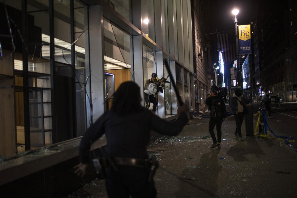Police run towards people as they jump out of a store with items they took hours after a solidarity rally calling for justice over the death of George Floyd Monday, June 1, 2020, in New York. Floyd died after being restrained by Minneapolis police officers on May 25. (AP Photo/Wong Maye-E)