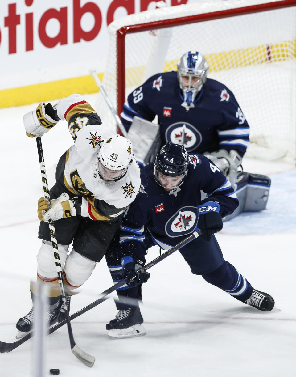 Winnipeg Jets' Neal Pionk (4) defends against Vegas Golden Knights' Paul Cotter (43) during second-period NHL hockey game action in Winnipeg, Manitoba, Thursday, Oct. 19, 2023. (John Woods/The Canadian Press via AP)