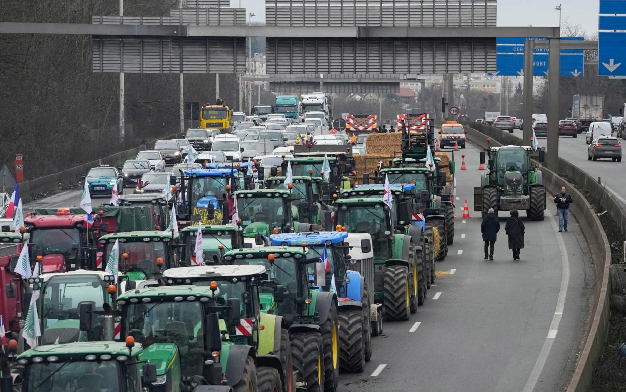 Tractors obstruct a highway north of Paris, but two of the major farmers' unions have now called for such blockades to be suspended