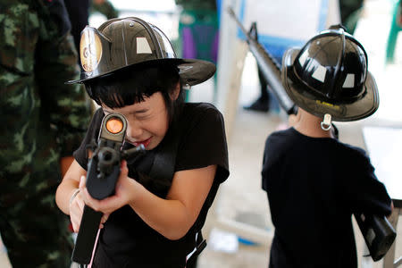 Children play with weapons during Children's Day celebration at a military facility in Bangkok, Thailand January 14, 2017. REUTERS/Jorge Silva