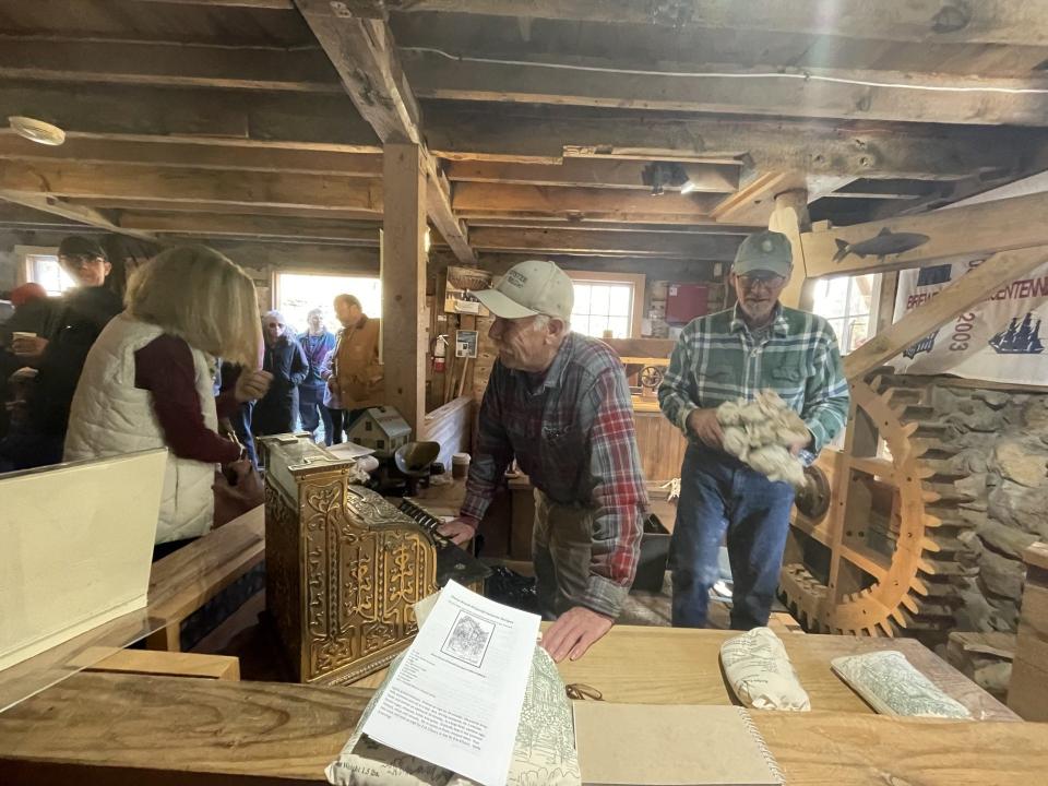 Head miller Doug Ericson helps customers on Saturday as volunteer assistant miller Scott Leonhardt brings bags of newly ground cornmeal to the counter during the holiday cornmeal sale at the Stony Brook Grist Mill in Brewster.