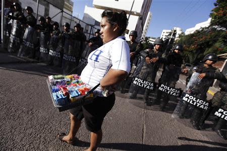 A street vendor walks past a police blockade during a protest by supporters of presidential candidate Xiomara Castro in Tegucigalpa November 25, 2013. REUTERS/Jorge Cabrera