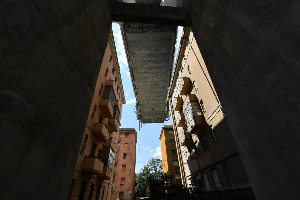 Buildings stand next to the partially collapsed Morandi highway bridge in Genoa, Italy, on Thursday, Aug. 16, 2018. Tons of jagged steel, concrete and dozens of vehicles plunged as much as 45 meters (150 feet) on Tuesday, causing dozens of fatalities. (Luca Zennaro/ANSA via AP)