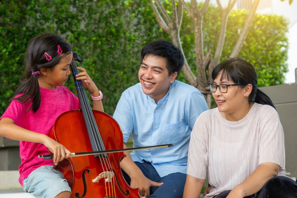 girl playing cello with her family at outdoor park