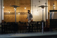 A man walks past a mostly empty outdoor seating area for a restaurant Thursday, Nov. 19, 2020, in Santa Monica, Calif. California Gov. Gavin Newsom is imposing an overnight curfew as the most populous state tries to head off a surge in coronavirus cases. On Thursday, Newsom announced a limited stay-at-home order in 41 counties that account for nearly the entire state population of just under 40 million people. (AP Photo/Marcio Jose Sanchez)