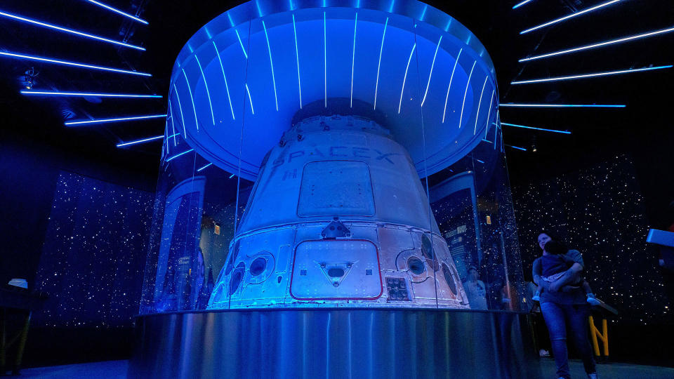 a white space capsule on display in a museum, lit up by blue lighting in a dark room