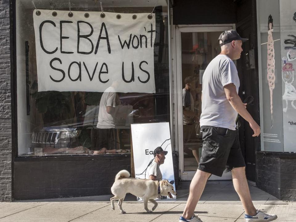  A pedestrian walking his dog walks past a store on Toronto’s Dundas Street West stating ‘CEBA Won’t Help Us’ during the COVID-19 pandemic in 2020.