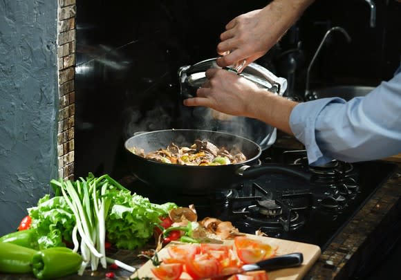 A home cook adds spices to a simmering pot.