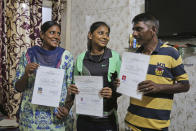 Radhika Gill, center, with her father Bhittu Gill and mother Shaloo Gill display their domicile certificates in Jammu, India, July 30, 2020. A year after India ended disputed Kashmir's semi-autonomous status and downgraded it to a federally governed territory, authorities have begun issuing residency and land ownership rights to outsiders for the first time in almost a century. Documents accessed and reviewed by The Associated Press show at least 60,000 have gained residency in the last two months including Hindu refugees, Gurkha soldiers and bureaucrats. (AP Photo/Channi Anand)