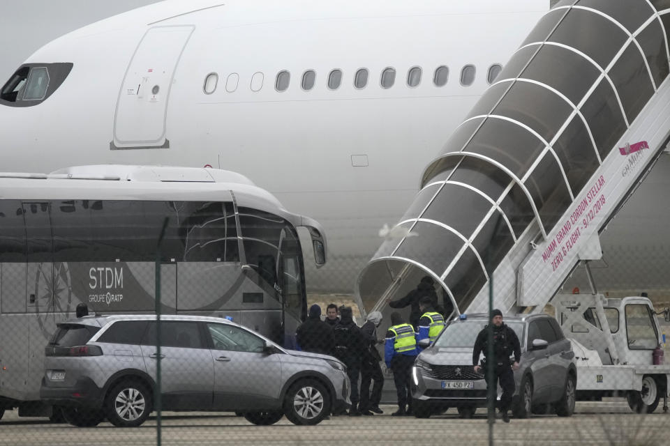 Men board the plane grounded by police at the Vatry airport , Monday, Dec. 25, 2023 in Vatry, eastern France. A charter plane grounded in France for a human trafficking investigation is scheduled to leave Monday for India, after an exceptional holiday ordeal that left some 300 Indians en route for Central America blocked inside a rural French airport for four days. (AP Photo/Christophe Ena)