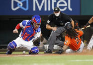 Baltimore Orioles' Freddy Galvis, right, slides home safely as Texas Rangers catcher Jonah Heim, left, cannot handle the throw as umpire Shane Livensparger, center, looks on during the seventh inning of a baseball game in Arlington, Texas, Saturday, April 17, 2021. (AP Photo/Ray Carlin)