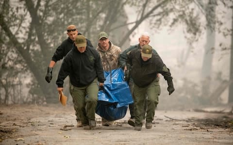 Yuba County Sheriff officers carry a body away from a burned residence in Paradise, California - Credit: AFP