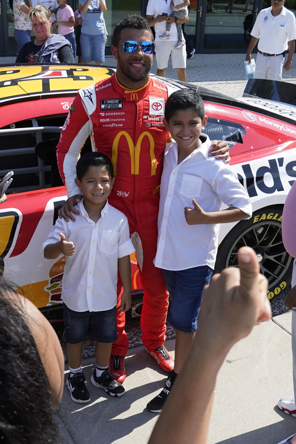 NASCAR driver Bubba Wallace poses with two youngsters at Navy Pier on Tuesday, July 19, 2022, Chicago during a promotional visit to announce a Cup Series street race to be held July 2, 2023, in the city. (AP Photo/Charles Rex Arbogast)