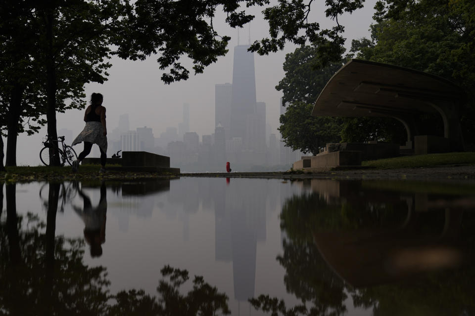 A person walks along the shore of Lake Michigan as the downtown skyline is blanketed in haze from Canadian wildfires Tuesday, June 27, 2023, in Chicago. (AP Photo/Kiichiro Sato)