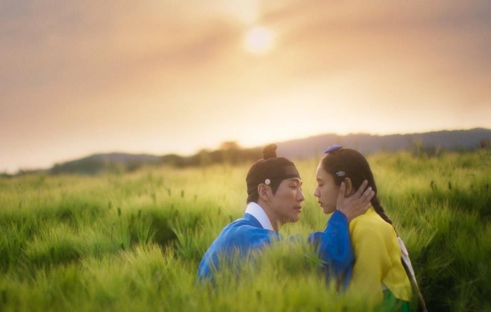 a couple wearing joseon-era historical costumes are about to kiss while sitting in a field, in a still from the k-drama 'my dearest'