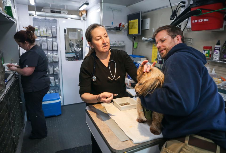 Veteranarian Corey Evans, center, prepares to give an shot to a dog as Frank Hanlon holds the animal inside the Care-A-Van outside the Kentucky Humane Society. Assistant Kelly Faye is at left. The van -- which sometimes will travel to certain areas of the Louisville metro area -- helps provide low cost basic vet services.