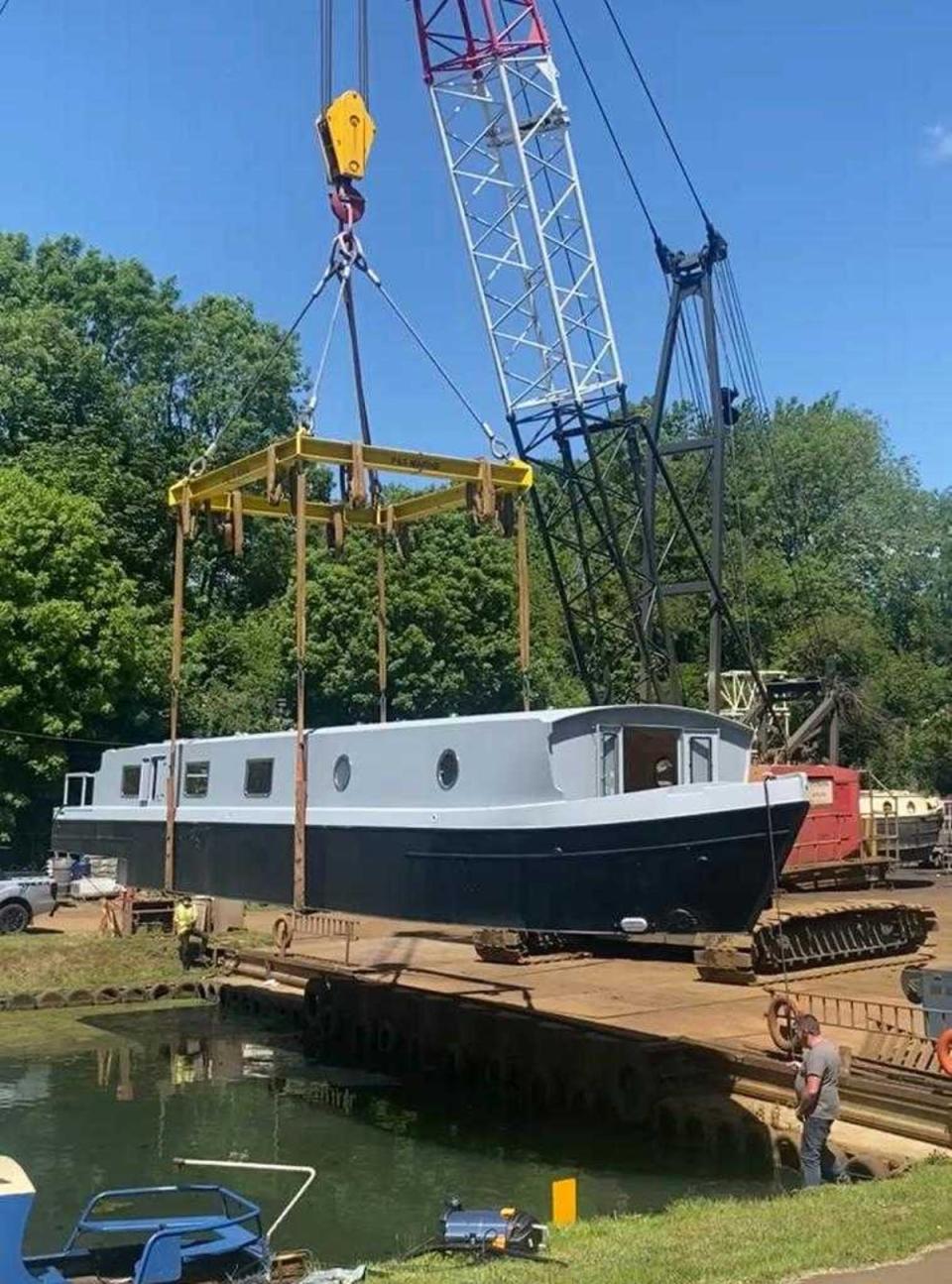 The couple’s brand new shell of a boat is lowered onto the River Lea (Supplied)