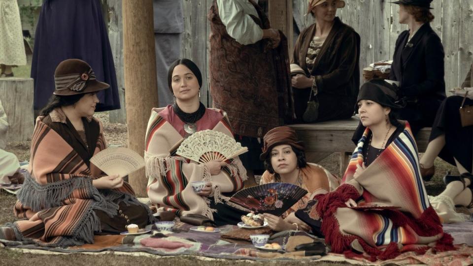 Osage women sit on the ground wrapped in blanket in Killers of the Flower Moon