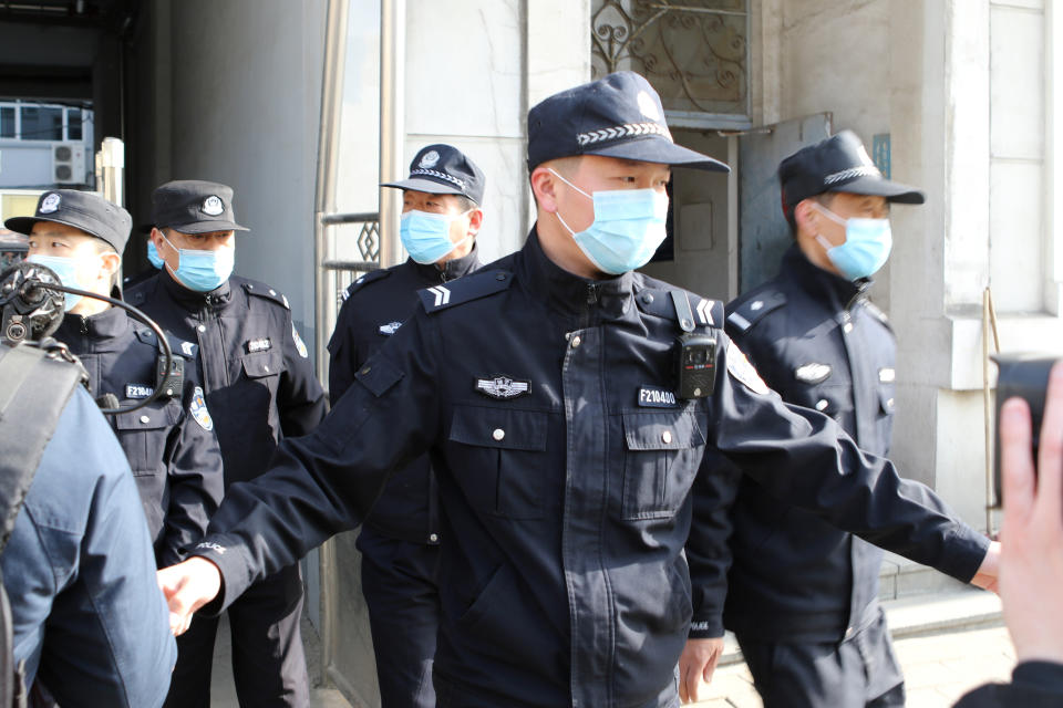 Security officers stand guard as police vehicles arrive at a court building in Dandong in northeastern China's Liaoning Province, Friday, March 19, 2021. China was expected to open the first trial Friday for Michael Spavor, one of two Canadians who have been held for more than two years in apparent retaliation for Canada's arrest of a senior Chinese telecom executive. (AP Photo/Ken Moritsugu)
