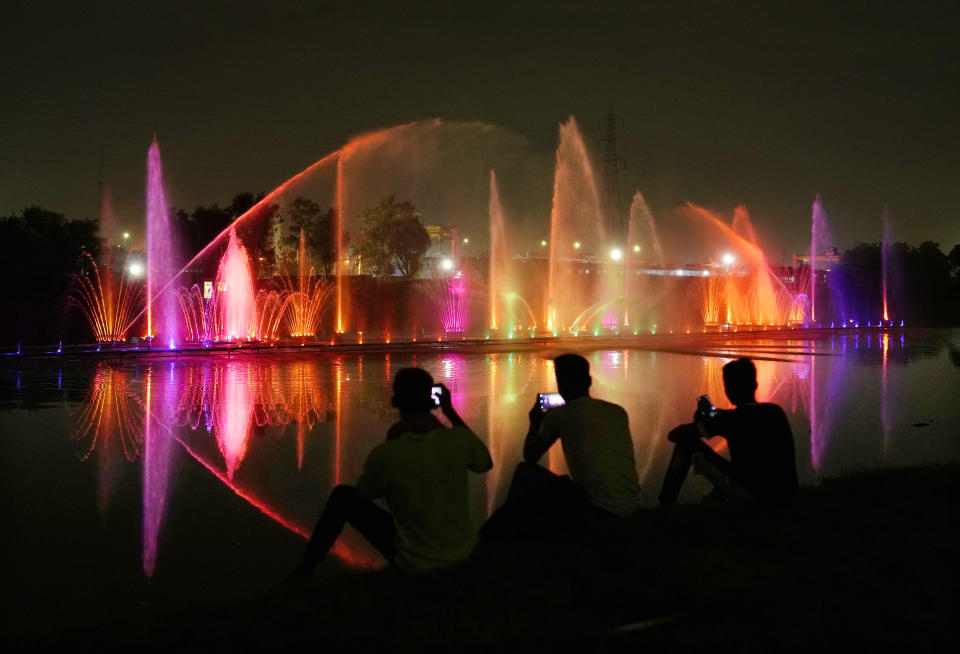 People watch a test run of a musical fountain in a newly constructed park near the banks of the river Yamuna, for the G20 Summit, in New Delhi, India, Friday, Aug. 25, 2023. In July, a report by a group of rights activists found the preparations for the G-20 Summit have resulted in the displacement of nearly 300,000 people, and at least 25 shantytowns and multiple night shelters for homeless were razed to the ground and turned into parks. (AP Photo/Manish Swarup)