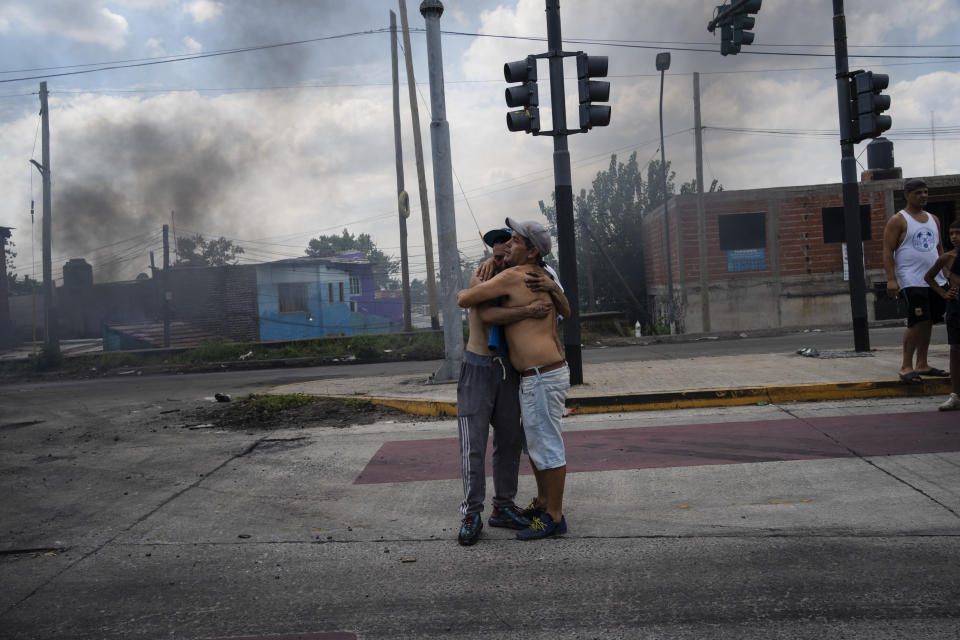 Jonathan Faundez, 23, left, is embraced by a fellow resident at a road block set up by locals to protest the arrest of some of his relatives in the Puerta 8 suburb north of Buenos Aires, Argentina, where police say contaminated cocaine may have been sold, Friday, Feb. 4, 2022. A batch of cocaine has killed at least 23 people and hospitalized many more in Argentina, according to police. (AP Photo/Rodrigo Abd)