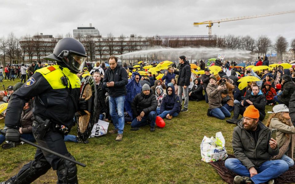 Police officers try to disperse anti-lockdown protesters at the Malieveld in The Hague - Shutterstock