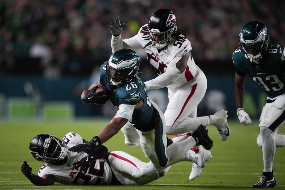 Philadelphia Eagles running back Saquon Barkley (26) falls with the ball near Atlanta Falcons cornerback Clark Phillips III, bottom, and Atlanta Falcons defensive end James Smith-Williams during the second half of an NFL football game Monday, Sept. 16, 2024, in Philadelphia. (AP Photo/Matt Slocum)