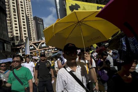 A pro-democracy protester holds a yellow umbrella, the symbol of the Occupy Central movement, during a march to demand universal suffrage in Hong Kong, China July 1, 2015. REUTERS/Tyrone Siu