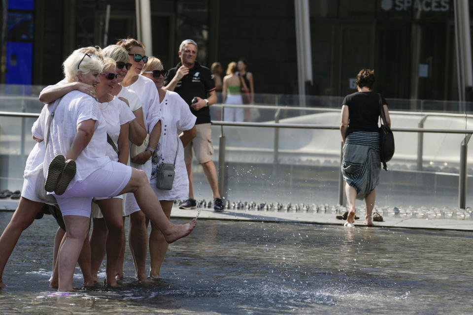 Tourists cool off in a public fountain in Milan, Italy, Saturday, July 15, 2023. Temperatures reached up to 42 degrees Celsius in some parts of the country, amid a heat wave that continues to grip southern Europe. (AP Photo/Luca Bruno)